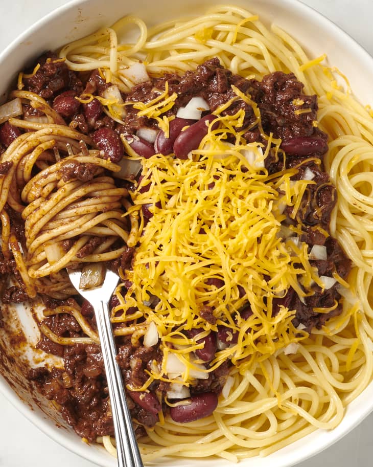 cincinnati chili in a bowl topped with cheese and a fork twirling it