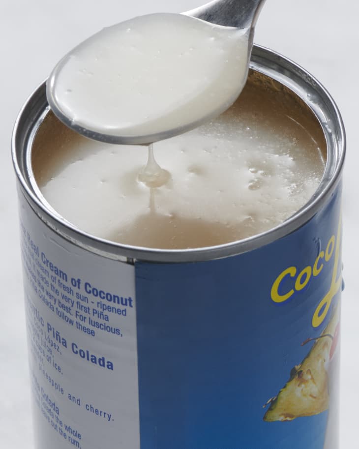 someone pulling cream of coconut out of a can with spoon