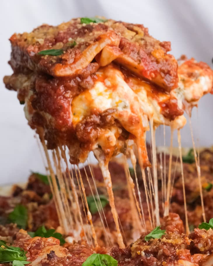 slice of lasagna with stringy cheese being pulled out of pan