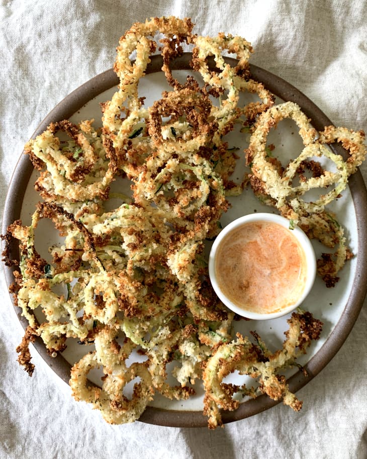 zucchini fries on a pan next to sauce