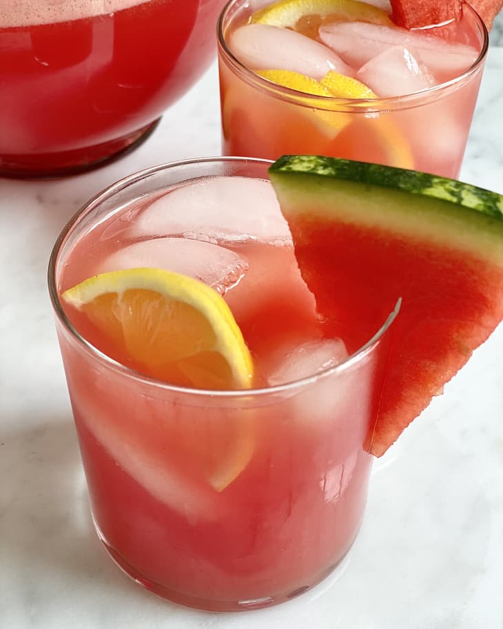 Glasses of watermelon lemonade with ice, lemon slices, and watermelon wedges.