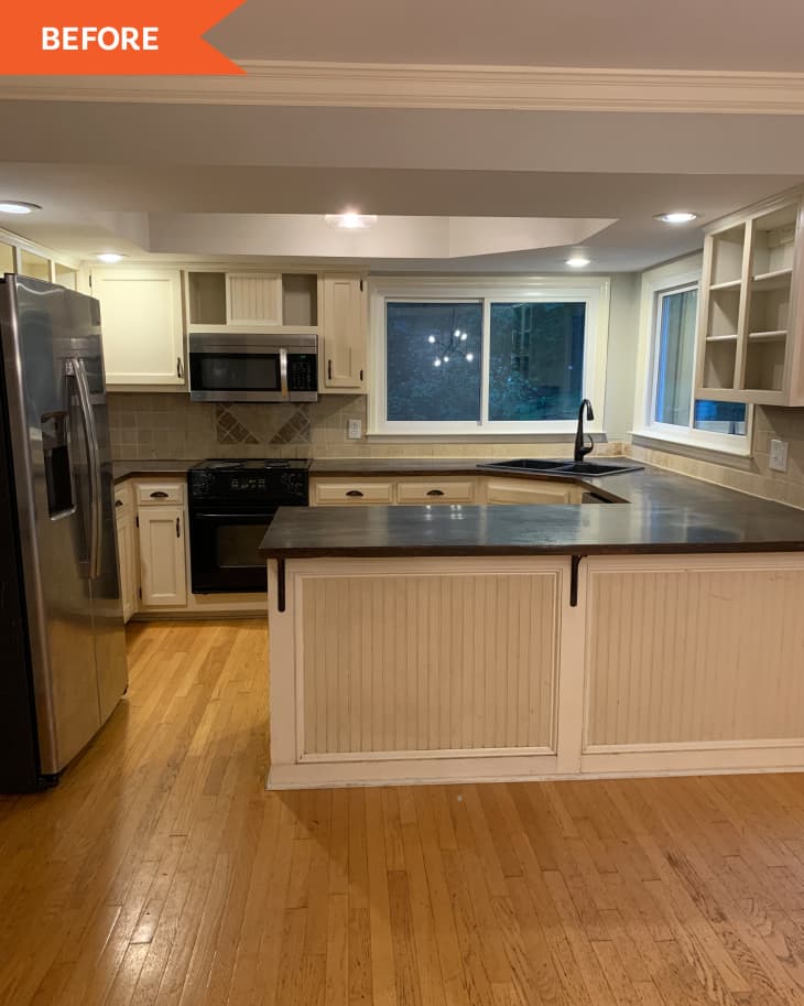 Kitchen with wood floors, white cabinets, stainless steel appliances, and a dark countertop island under recessed lighting.