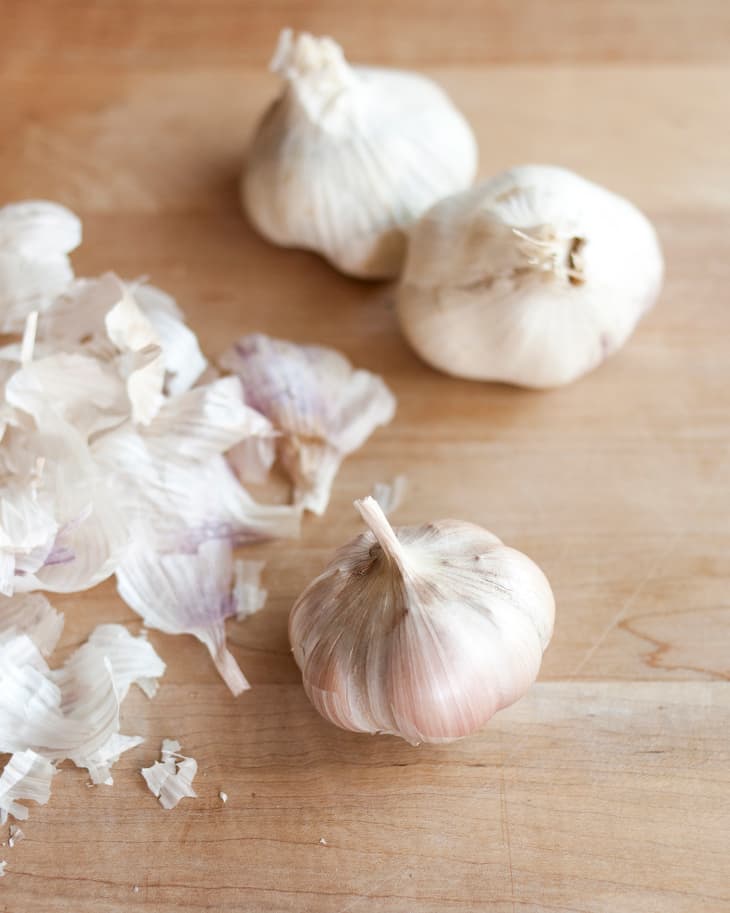 three heads of garlic next to garlic skin