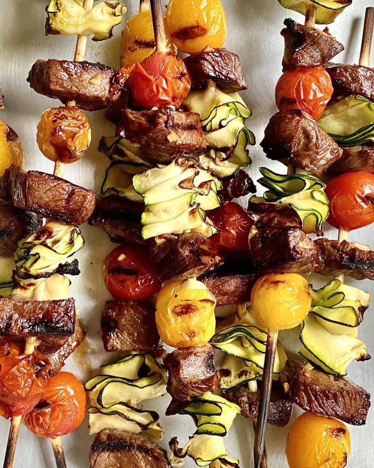 Photograph of steak kebabs in on a metal quarter sheet tray.