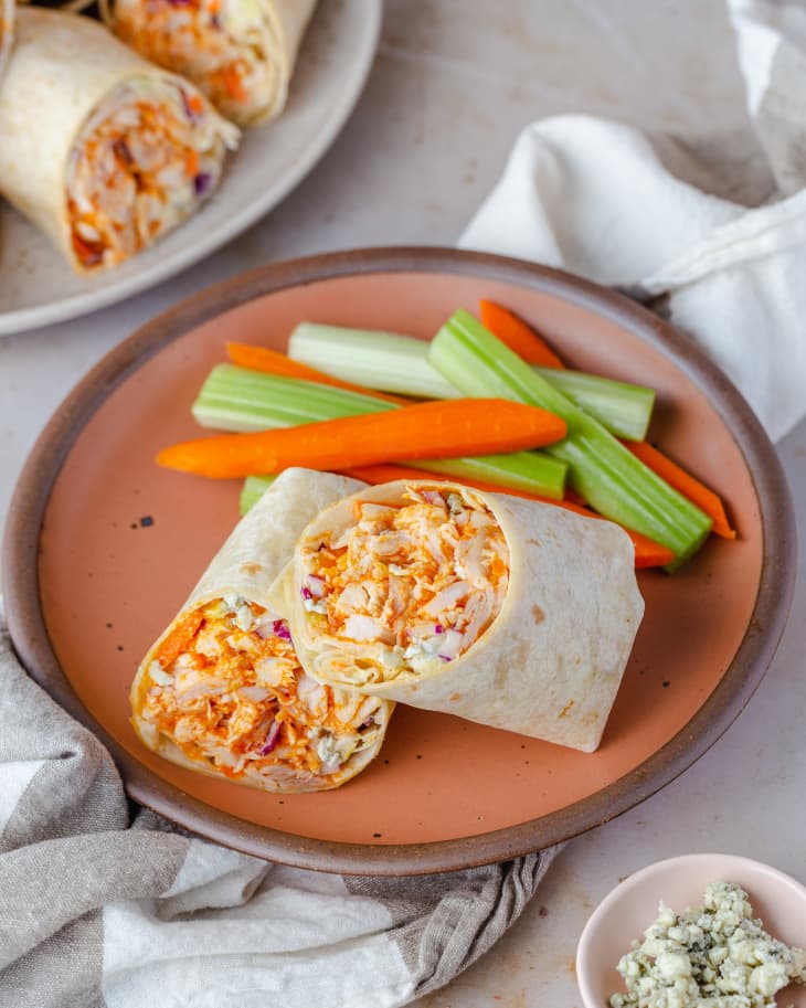 Photo of buffalo chicken wrap on a plate with carrot and celery sticks.