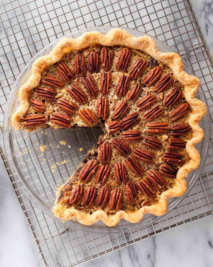 Photograph of chocolate pecan pie in plate on a wire rack.