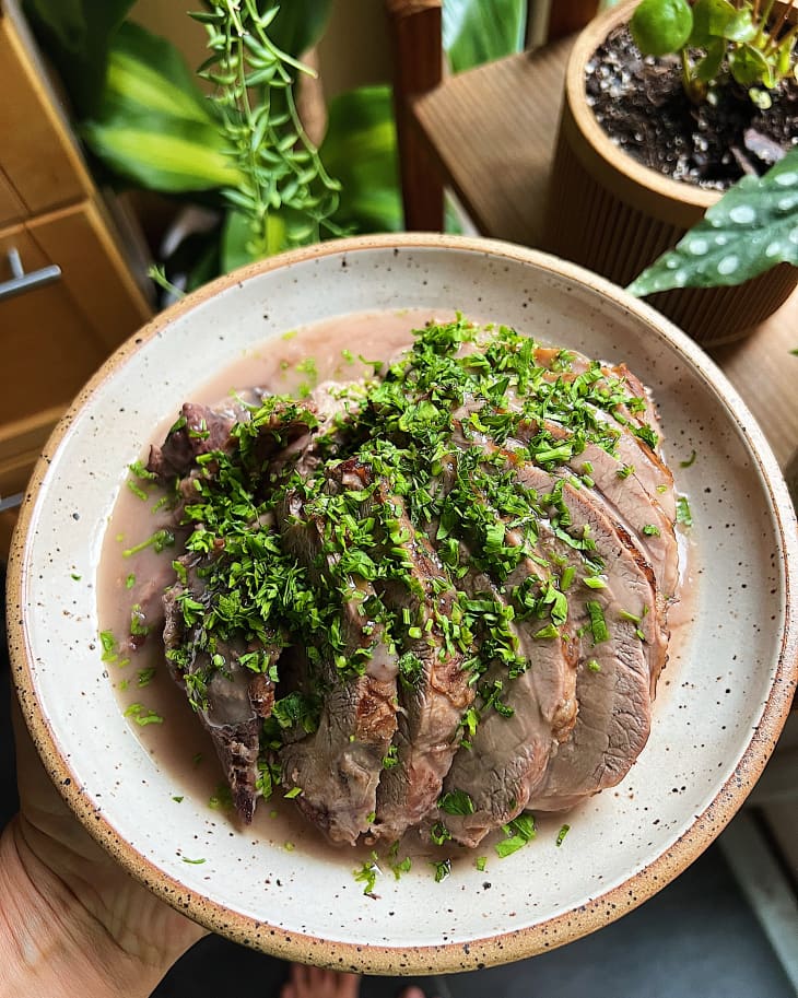 slices of lamb on a plate with herbs on top