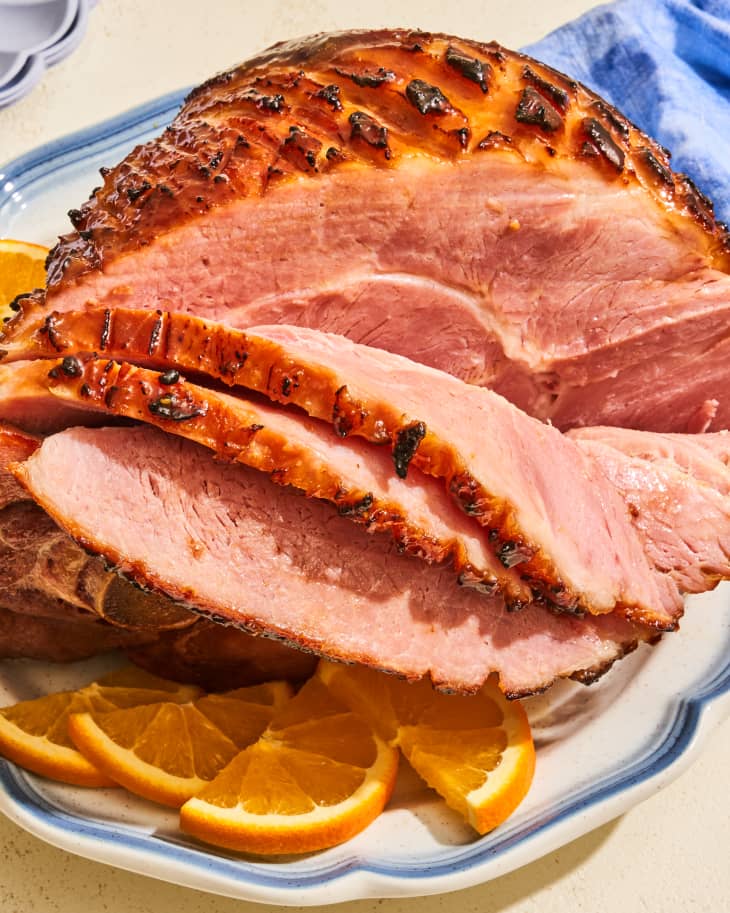 Bourbon glazed ham partially sliced and on a platter with orange slices