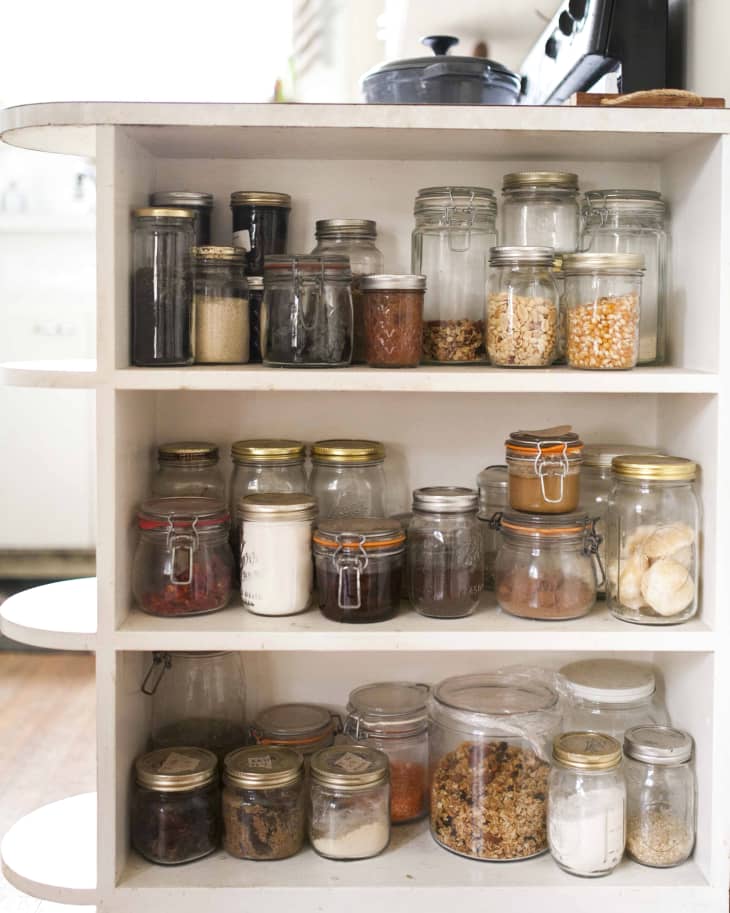A variety of jars used for storage in an open kitchen cabinet