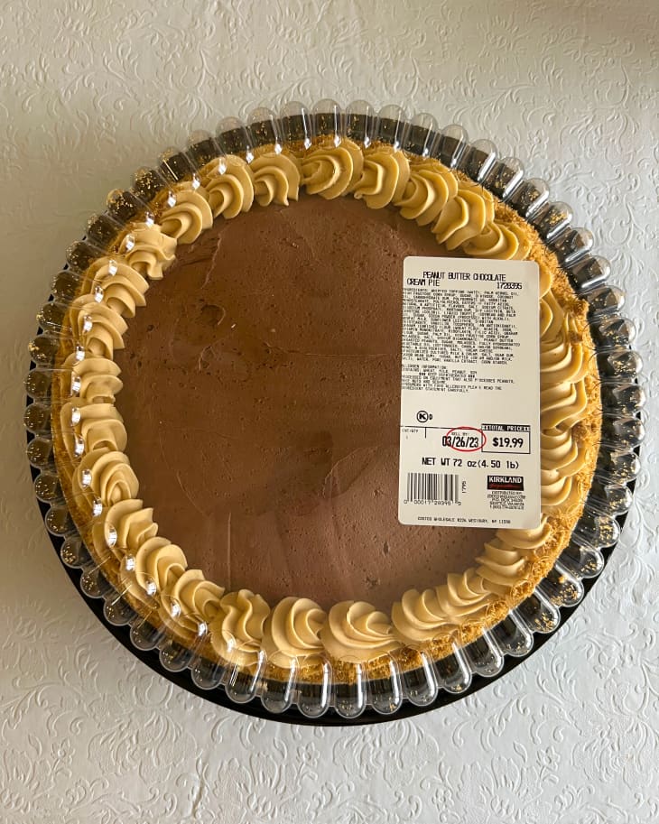 Costco Peanut Butter pie in plastic case on white surface.