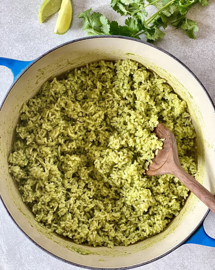 Arroz verde in a Dutch oven with a wooden spoon inside.