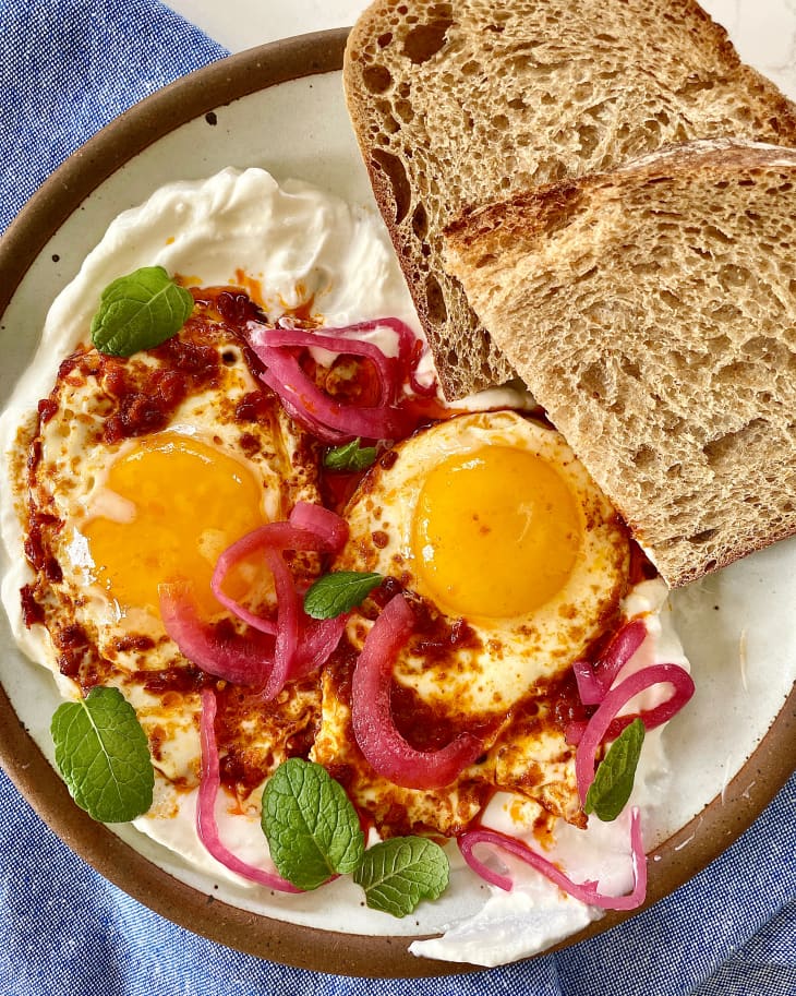 Harissa fried eggs on plate with a side of toasts.