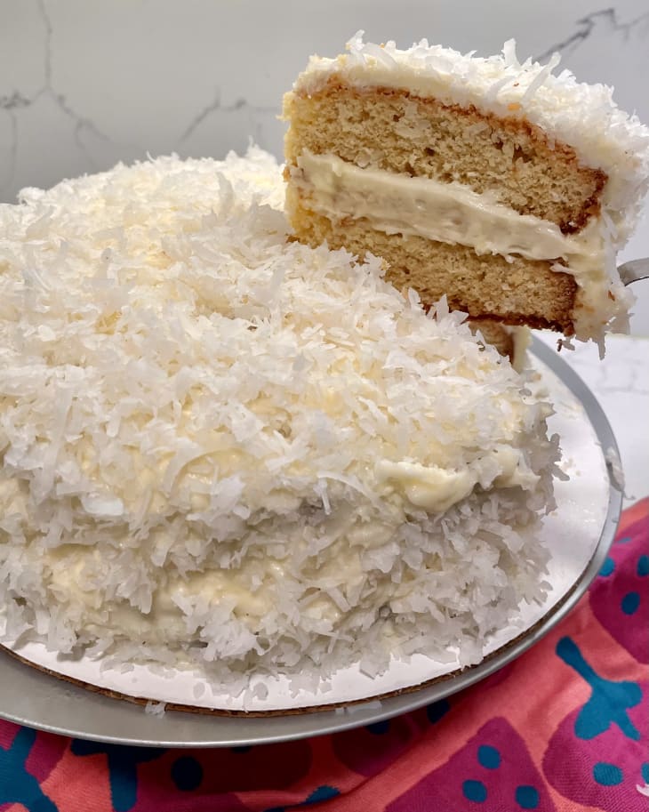 Someone lifting slice out of coconut cake.