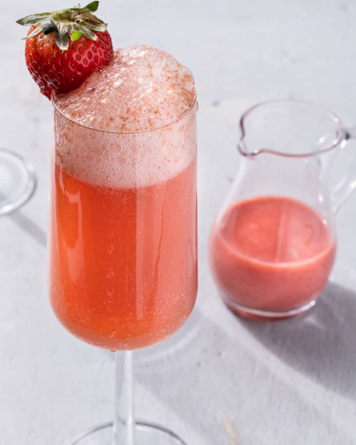 Strawberry mimosa in glass with small pitcher on the side.