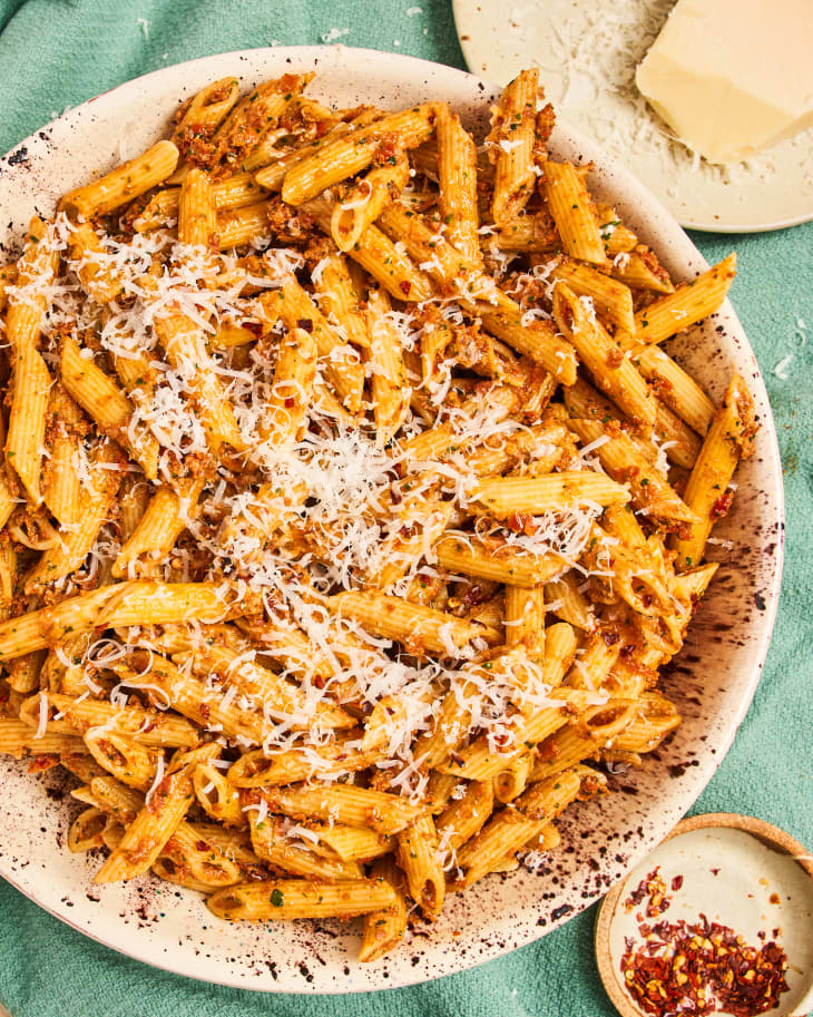 Pasta with sun-dried tomato pesto topped with cheese in a bowl.
