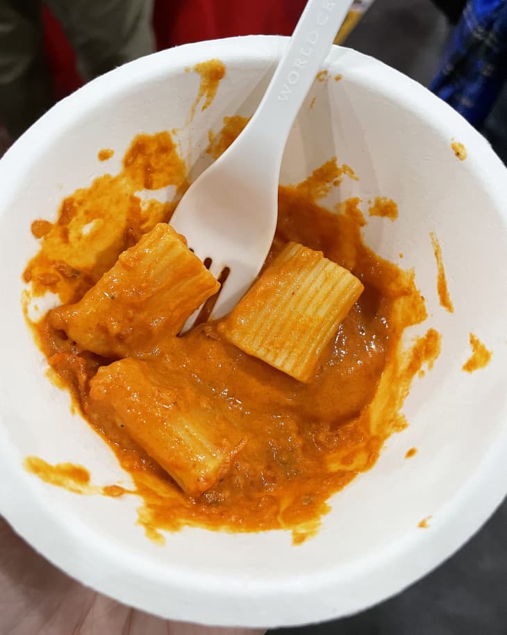 Rigatoni in spicy vodka carbone sauce in paper bowl with plastic fork