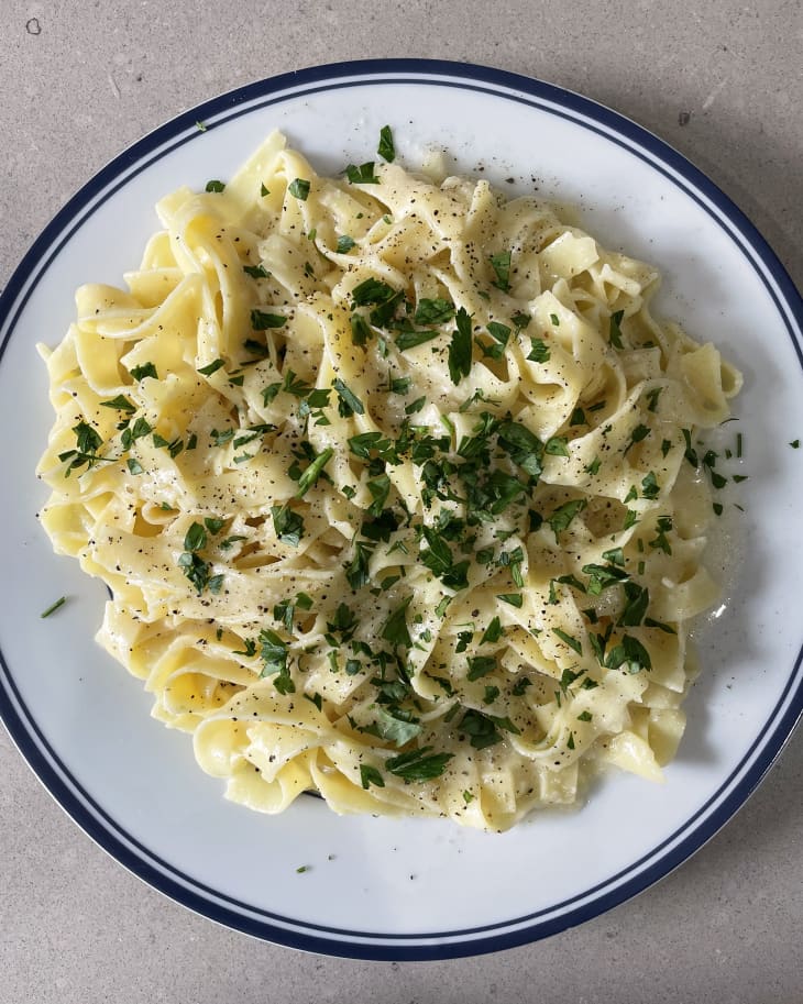 fettucine alfredo serving on a plate, garnished with herbs