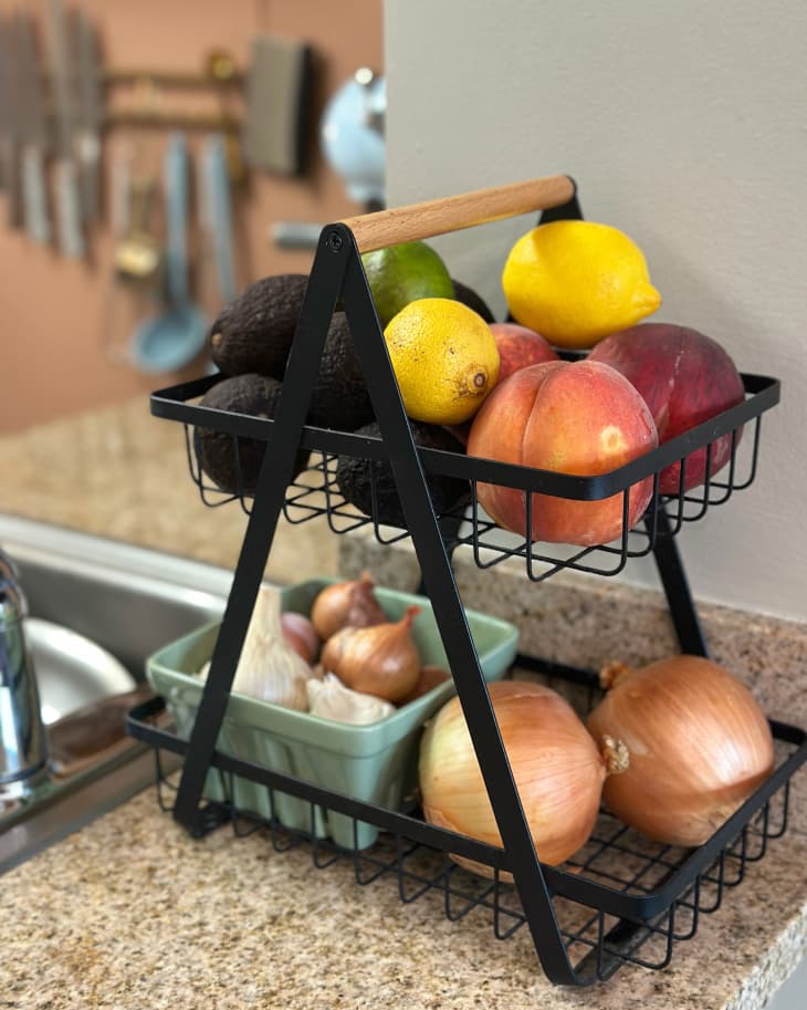 2 tiered fruit and vegetable stand full of fruits and vegetables on counter