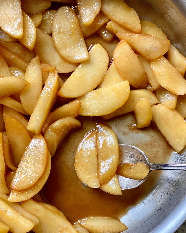 Caramelized apples on a spoon in a skillet.