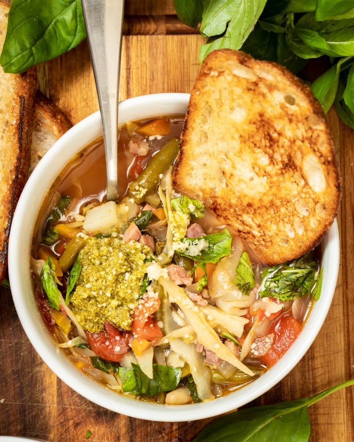 Minestrone soup in bowl with bread on the side.