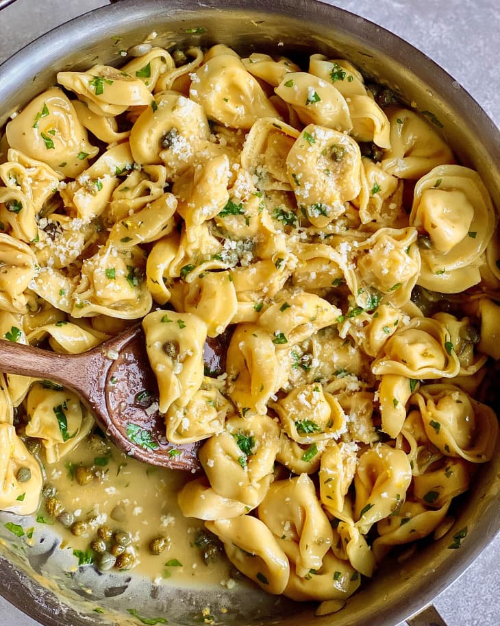tortellini pasta with capers, parsley, and parmesan in skillet with wooden spoon