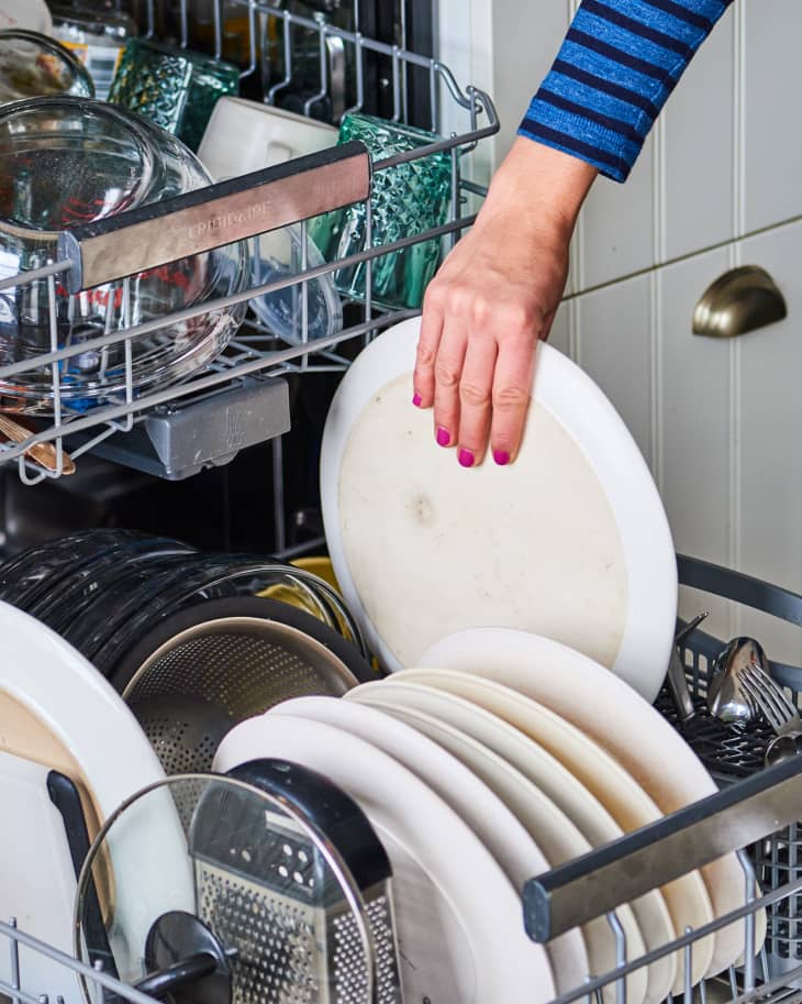 Someone putting plate into dishwasher.