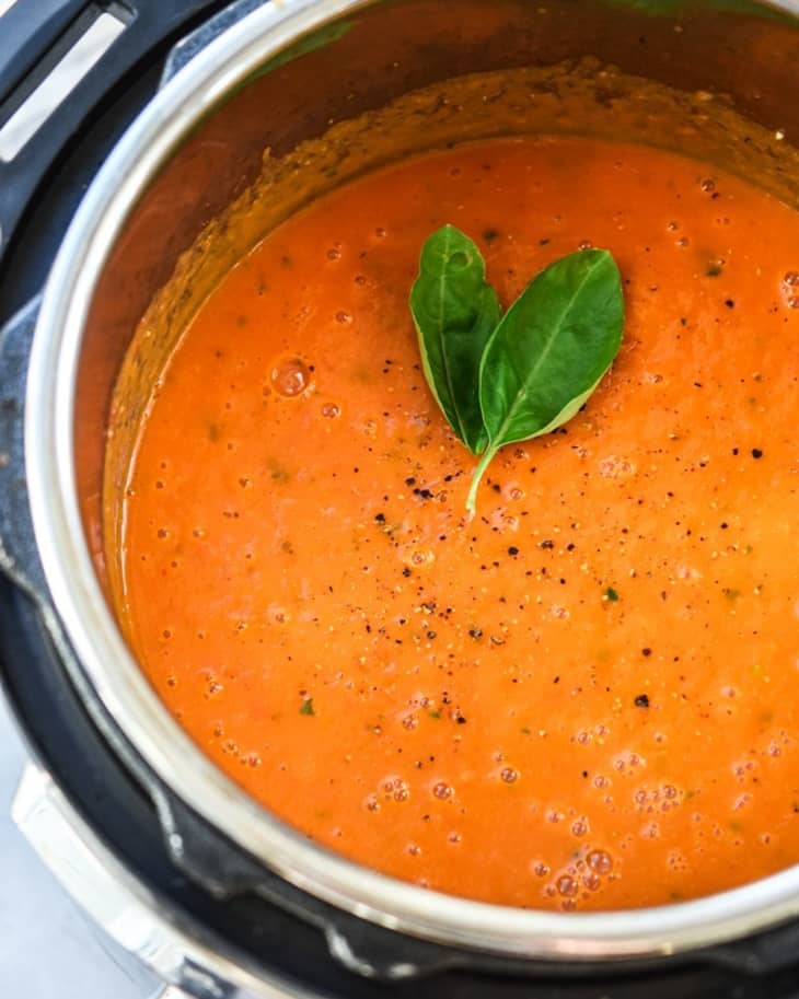 Tomato soup in an Instant Pot garnished with a fresh basil leaf.