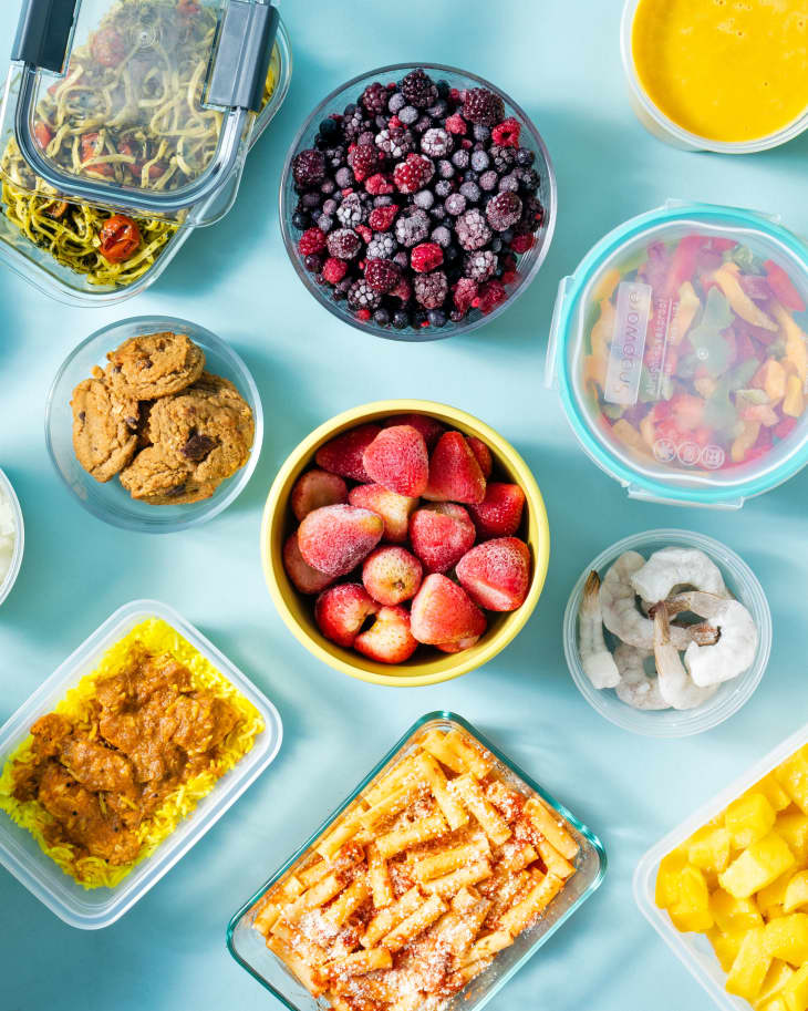 Variety of frozen foods in storage containers o blue surface.