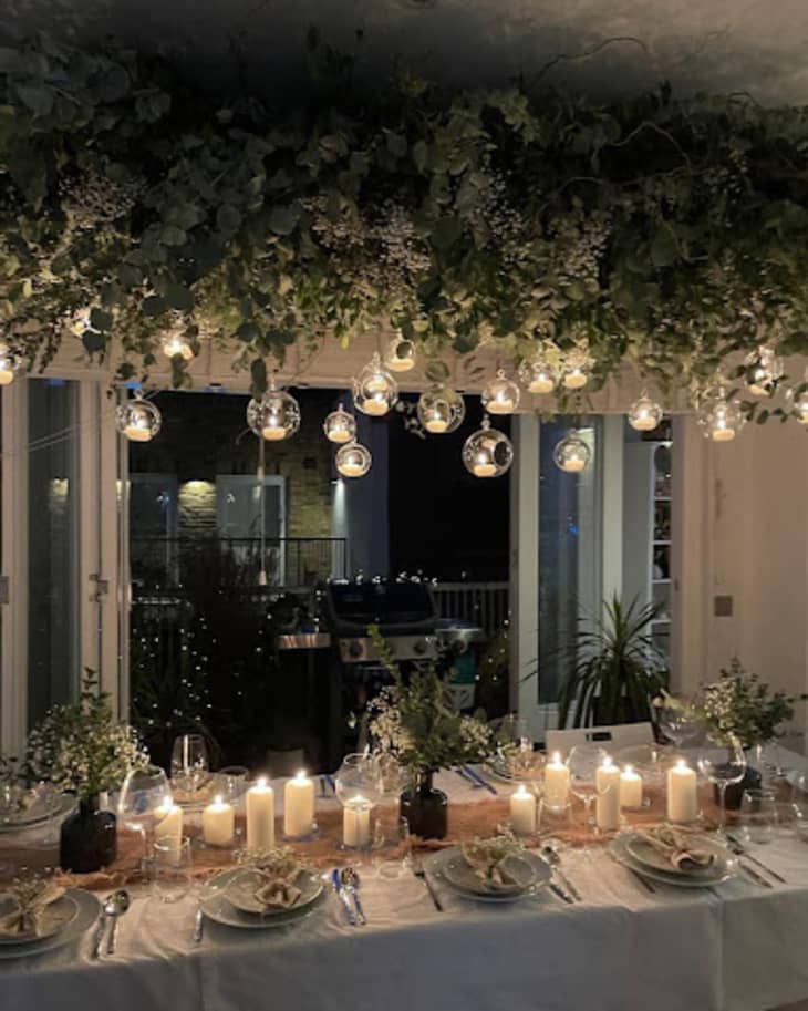 Holiday table with overhead garlands and small lights, candles on table