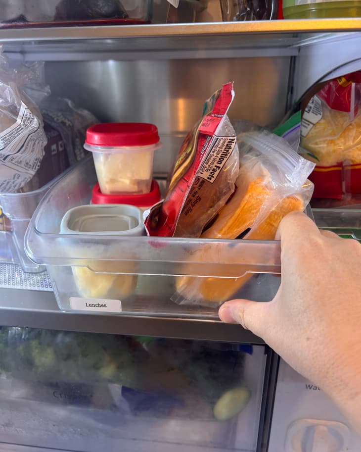 A hand reaching into a refrigerator