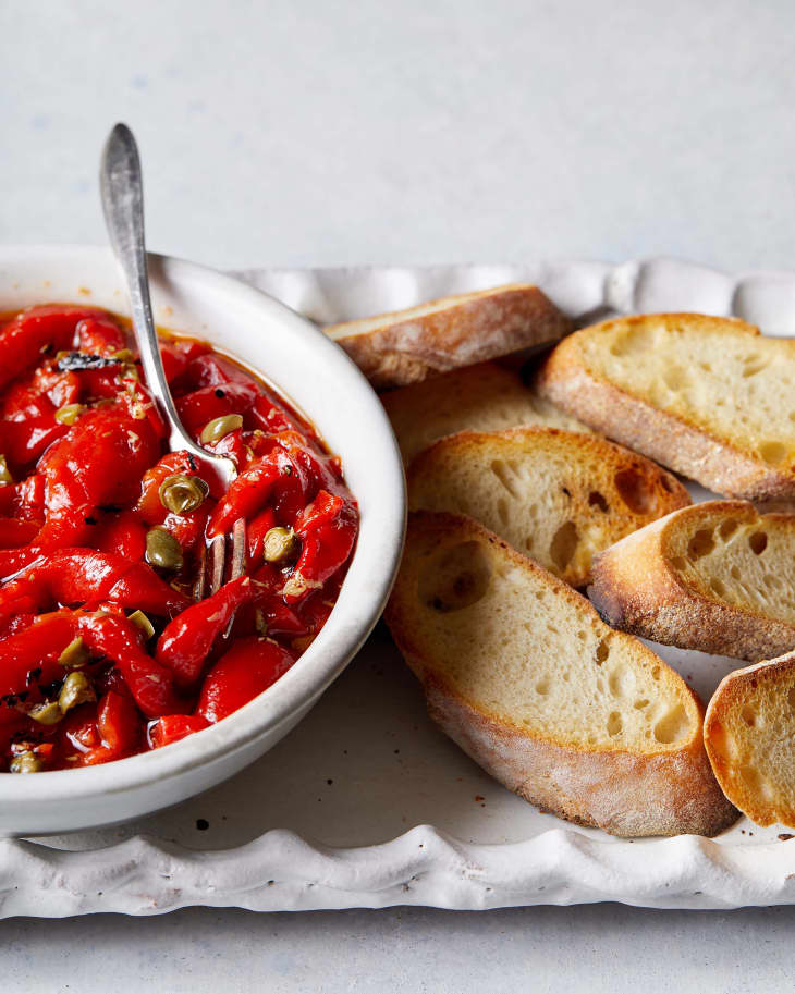 Slinky red peppers in bowl with crostini beside.