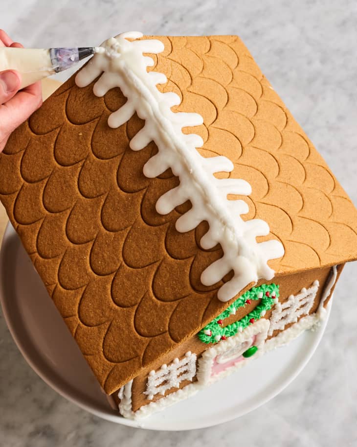 Decorating gingerbread house with icing.