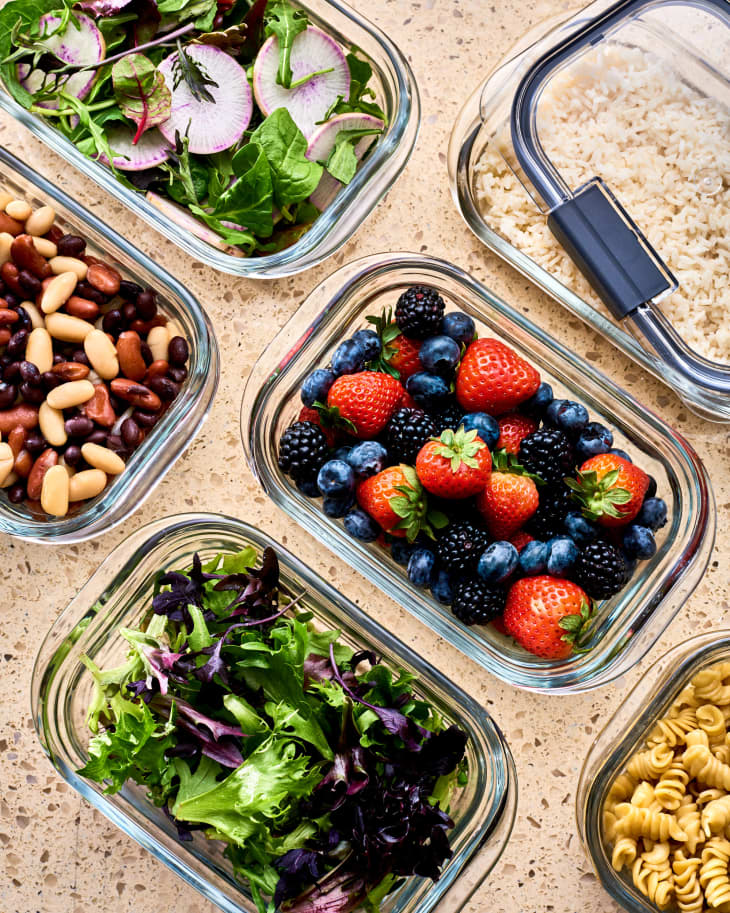 counter with glass containers full of food prep: berries, pasta, salad, beans