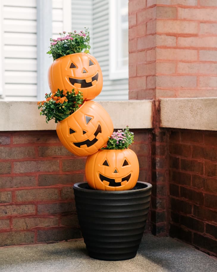 Plastic jack-o-lanterns used as planters on front porch.