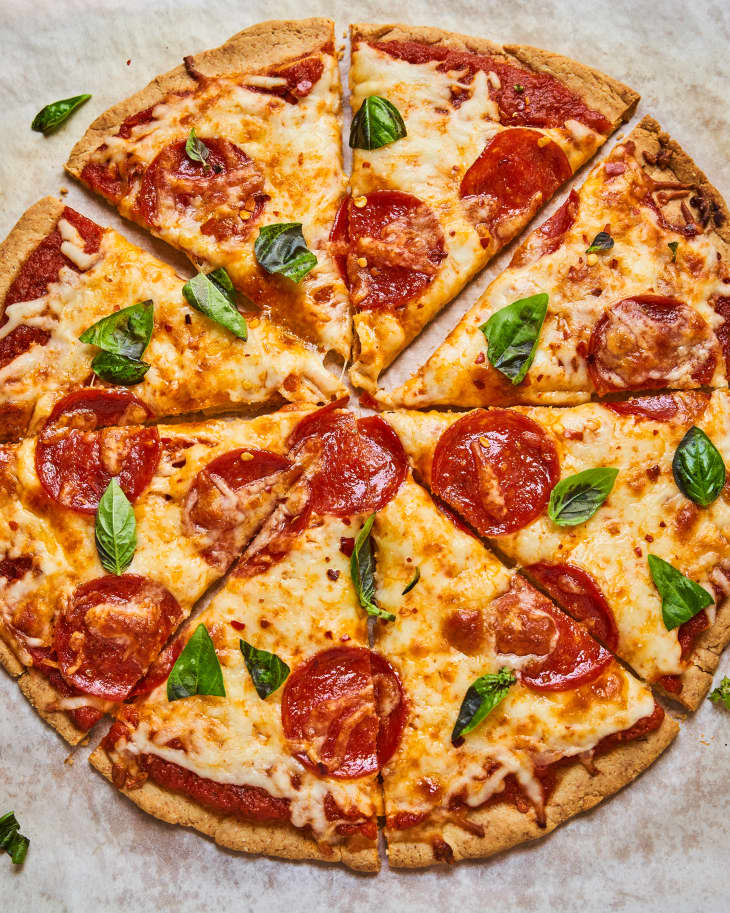 A whole pepperoni pizza with an Almond Flour Crust and basil on top, cut into eight slices
