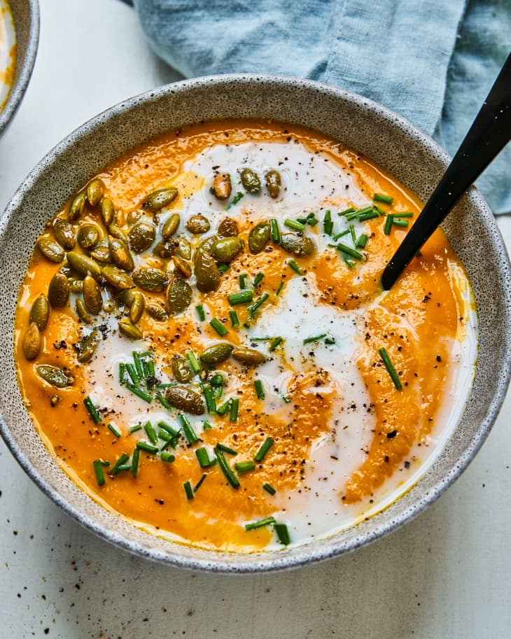 Carrot Ginger Soup with a cream and pine nut garnish, in a bowl