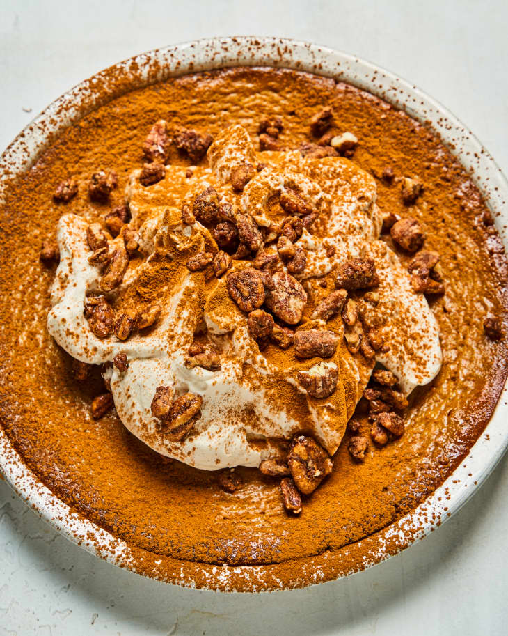 a whole, round, Crustless Pumpkin Pie, with whipped cream, cinnamon and nut topping