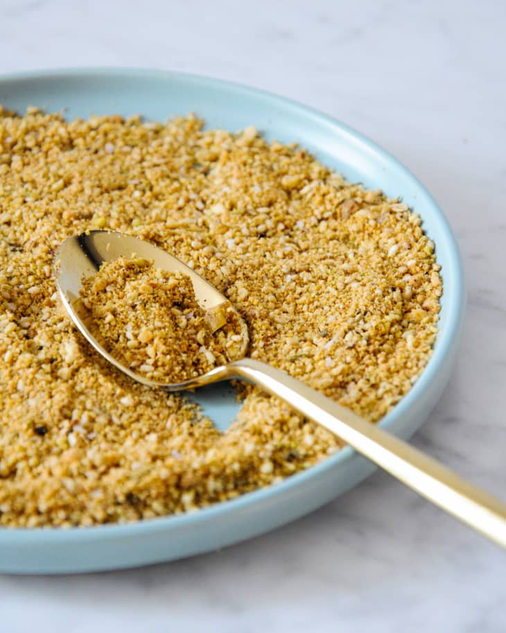 Dukkah (spice blend) in a blue bowl with a silver spoon