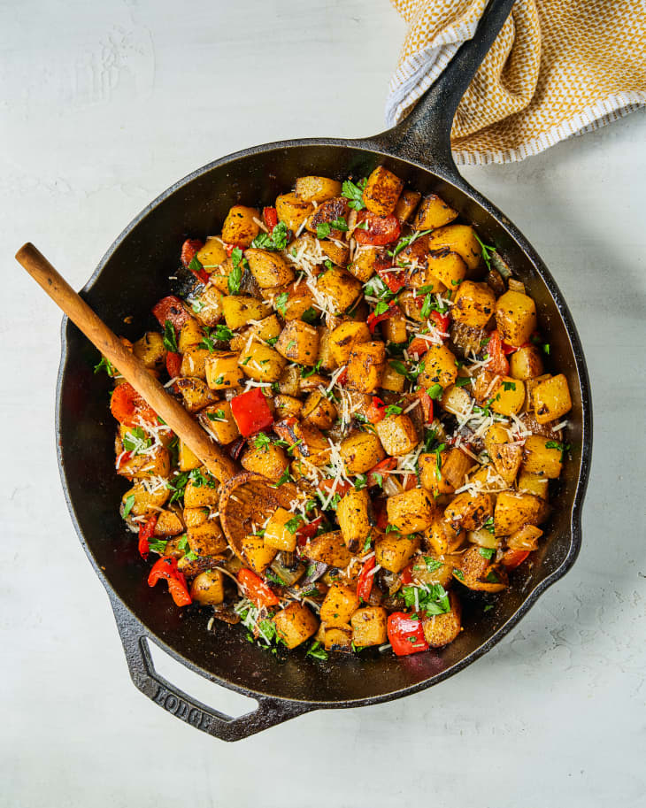 Potato Hash (diced potatoes and peppers, fried) in a skillet with a wooden spoon