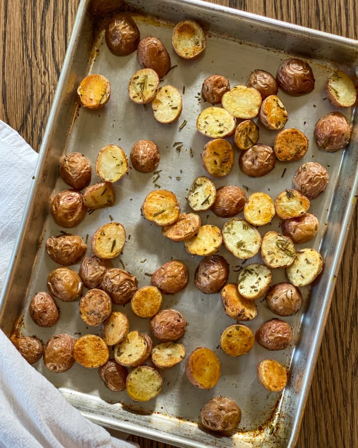 Roasted baby potatoes cut in halves, spread out on a pan.