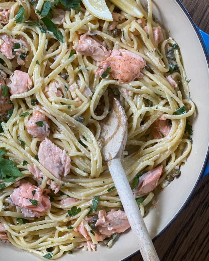 Salmon pasta (linguini, chunks of salmon and parsley) in a bowl with a fork in it.