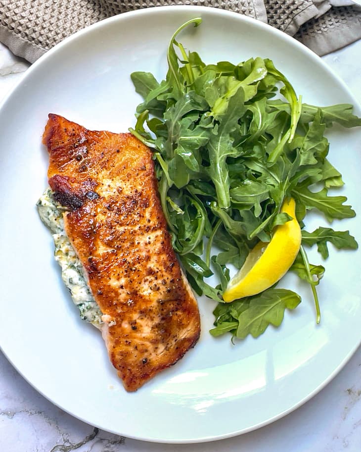 Salmon stuffed with spinach, cream, mozzarella and parmesan, pan-fried, and on a plate with an arugula side salad