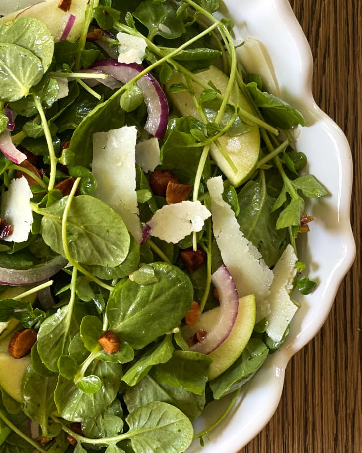 A closeup of a Watercress salad in a white dish