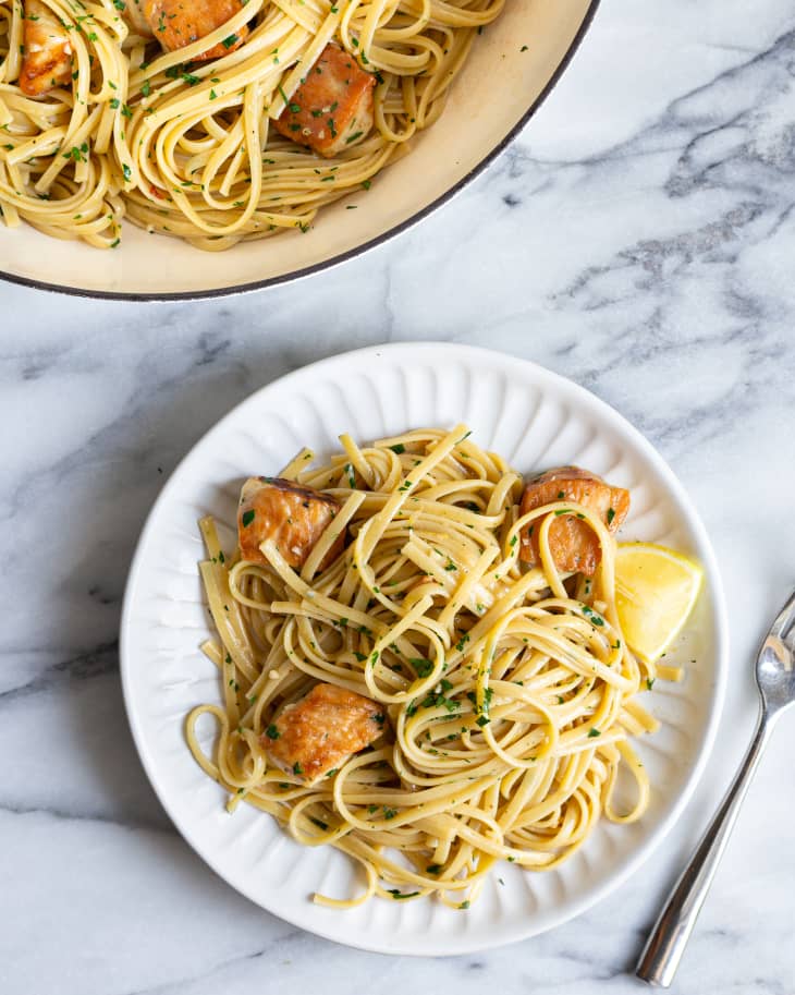 Chicken Scampi with linguini on a plate, with a fork on the plate and a platter with more Chicken Scampi  behind it