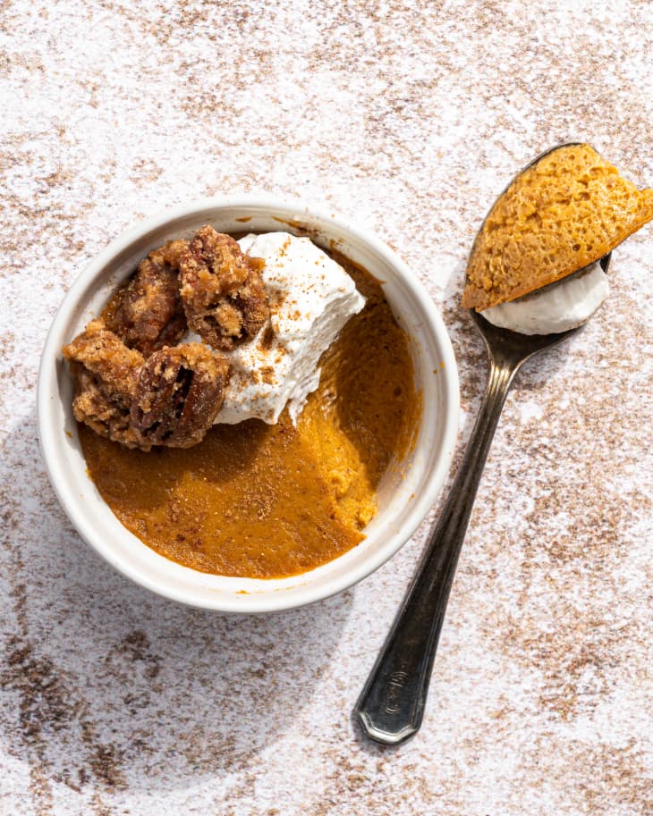 a ramekin of pumpkin custard with whipped cream on top, and a spoonful on the side