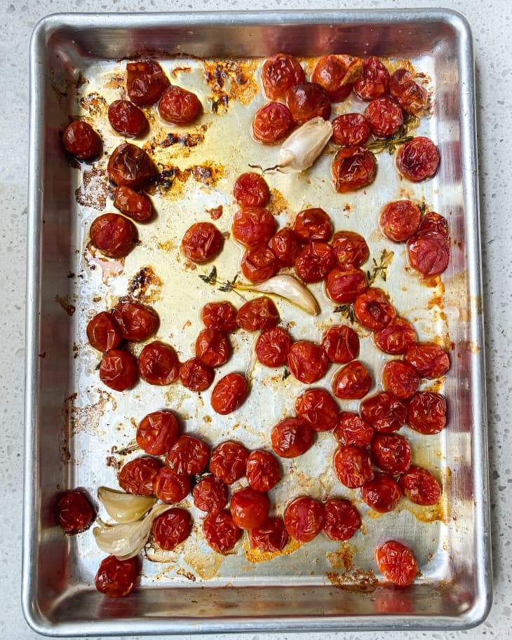 Roasted cherry tomatoes on a silver baking sheet.