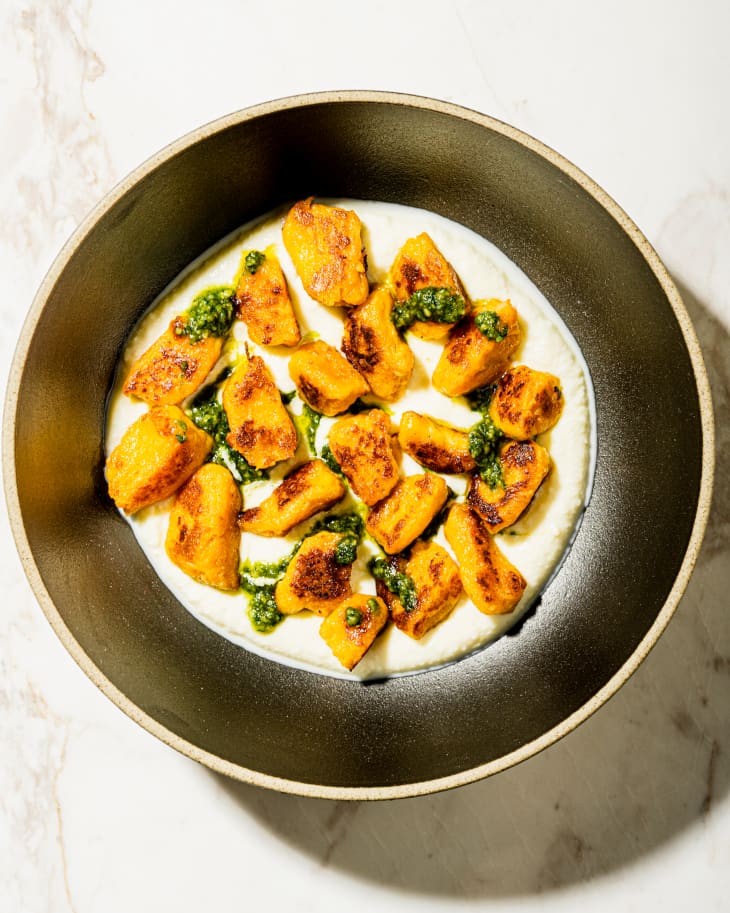 Sweet Potato Gnocchi  on a plate with a cream sauce and green garnish.