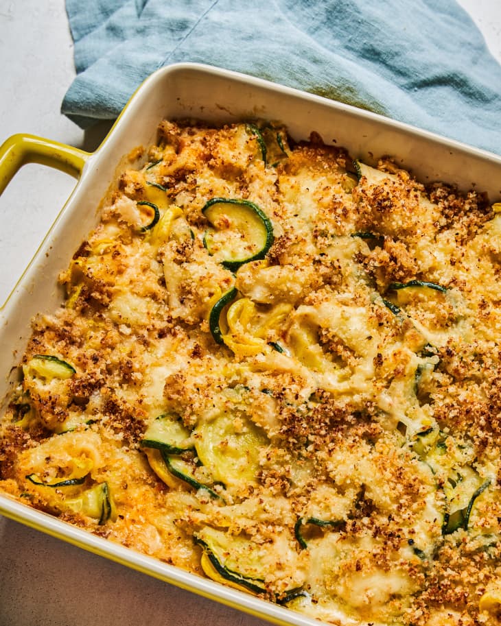 Zucchini and squash casserole in a dish with a gold handle