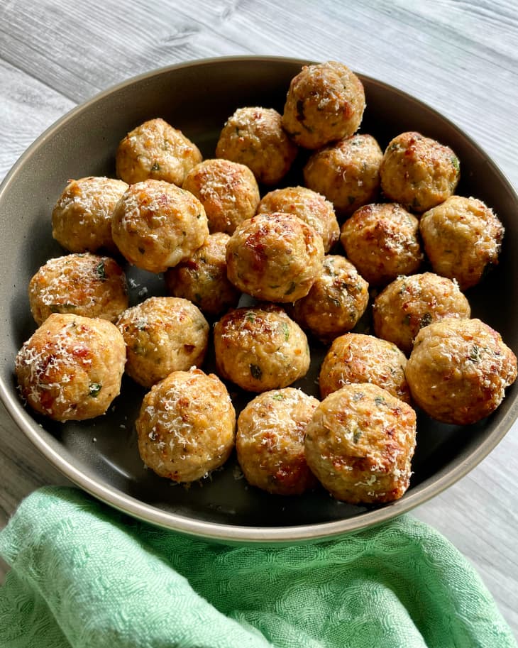 Baked turkey meatballs in a gray bowl, with a green linen napkin at the bottom.