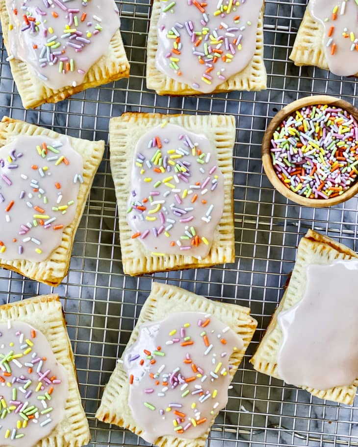 Homemade Pop Tarts with pink icing and pastel rainbow sprinkles on a cooling rack